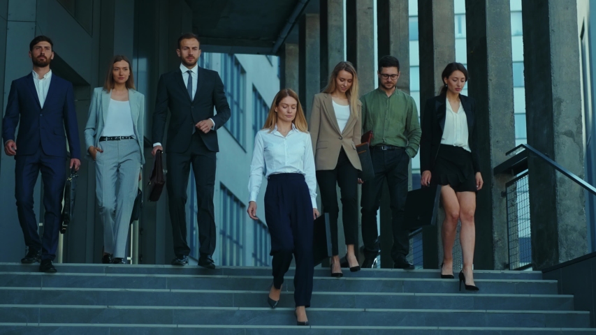 Professional company staff walking downstairs at office building. Successful and ambitious young team of co-workers and female boss. Cooperation. Career. Royalty-Free Stock Footage #1054967588