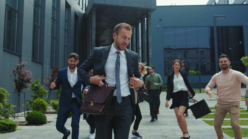 Multi-ethnic group of co-workers dancing funny on outdoor street. Happy satisfied business men and women with boss dancing on to rejoice corporate victory. | Shutterstock HD Video #1054967618