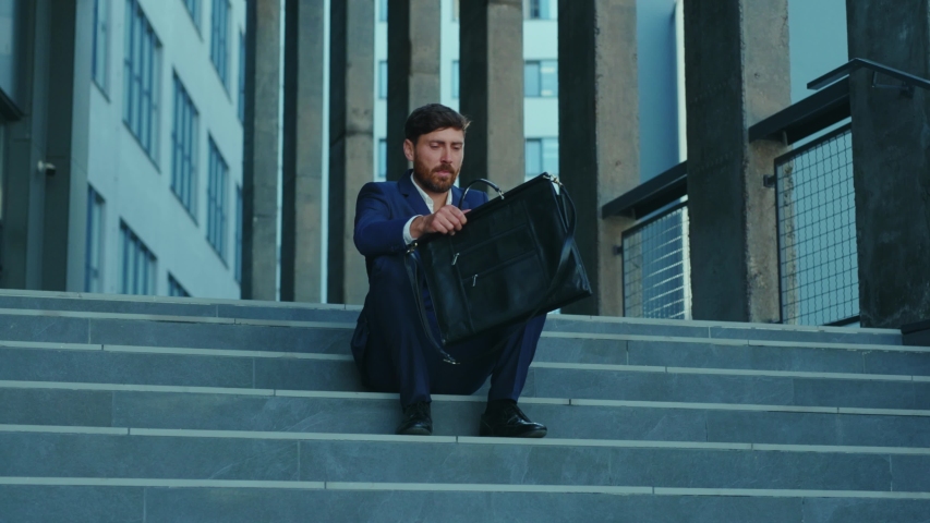 Sad furious office executive throwing his suitcase been fired lost job sitting on stairs frustrating. Unhappy fired businessman. Unemployment after lockdown. Crisis. Royalty-Free Stock Footage #1054967639