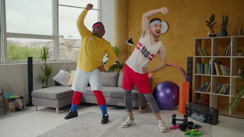 Funny grimacing sport freaks stretching in the living room. Multi-ethnic fat and slim guys doing sports routine exercising warm-up at home. Workout. Fun concept.