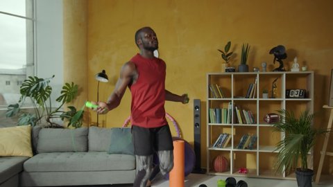 Active energetic black sportsman performing cardio workout jumping rope exercising in the living room. Training at home. Fitness. Sportsman. Healthy lifestyle.