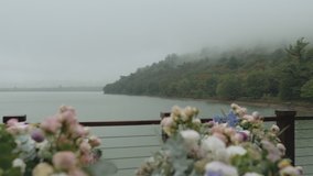  Wedding flower arch and decoration lake and mountains in fog on the background, close - up wedding arch with pink floral arrangement, slow motion, full hd
