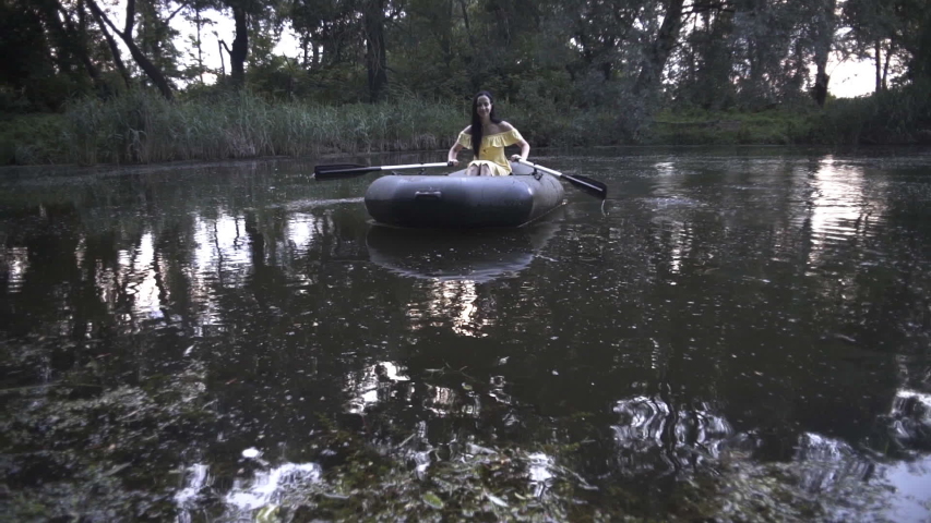beautiful girl swims in a boat on a lake in a fairy forest