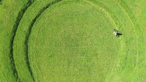 Girl cyclist riding in a circle on green grass, aerial view, circular rings