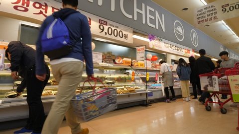 SEOUL, SOUTH KOREA - APRIL 01, 2018: Stalls at kitchen section of large supermarket in Seoul Station, unidentified people walk by with baskets and trolleys. Packages with cooked food lie on shelves
