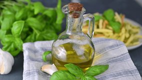 Olive oil in a bottle on the table, with fresh basil leaves, garlic. Ingredients for making pasta. Traditional italian food. Products for a healthy diet and health. 4k video