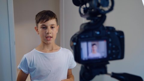 Boy videoblogger filming new vlog video with professional camera at home. Kid vlogger recording video movie for internet. Young blogger talking on video shooting.