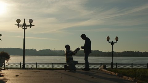 Gay Marriage Proposal Concept. Silhouette of Two men. Guy Gifts a Wedding Ring to His Fiance. Surprised Partner is Happy. Relationship Goals. LGBTQI, Pride Event, LGBT Pride Month, Gay Pride Symbol