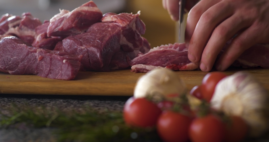 Chief`s Hand cutting Beef fillet on the Cut Board, preparing Meat. Brutal Mans`s Hands with a Knife slicing, cutting a delicate Beef fillet Meat on the cut board in the Kitchen. Beef or Veal meat on t | Shutterstock HD Video #1054990742