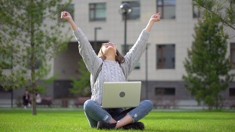 Happy university teenager girl female student with arms raised. Young woman receiving good news on laptop. student celebrating exams, admission to College, business great results win success victory