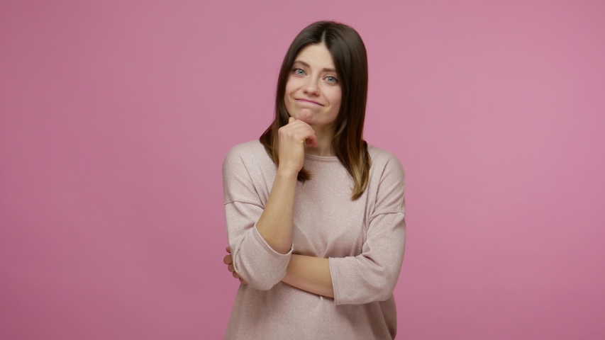 Confused upset brunette woman suspecting problem and thinking over solution, having doubts shrugging shoulders in bewilderment, pondering dilemma. indoor studio shot isolated on pink background Royalty-Free Stock Footage #1055003174