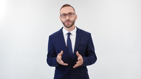 Smiling trendy man in suit talking standing isolated on white studio background. Friendly bearded business coach speaking and gesticulating having positive emotion. Shot on RED Raven 4k Cinema Camera