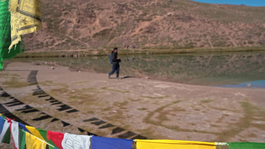 A traveller walking by a huge himalayan lake in spiritual quest