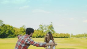Happy woman and man playing with ball in summer park. Low view ball rolling on green grass in field. Cheerful woman falling on ground in meadow. Happy boy playing ball with parents