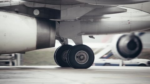 Close-up of the landing gear wheels / tyres on a modern twin-engined passenger aircraft. Aircraft is taxiing along the airport apron.