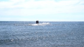 Mature couple walking alone towards the horizon in the middle of the sea on a sunny summer day. Stock video of summer holiday.