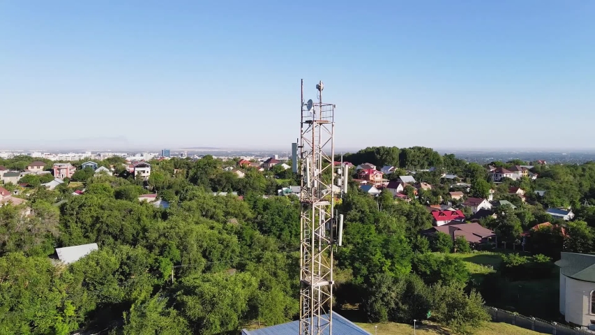 Aerial footage around a telecommunications tower with sector antennas of a mobile operator and radio relay equipment in the city. Telecommunication equipment in Kazakhstan. 5G technology. Telecomphone Royalty-Free Stock Footage #1055011862