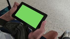 4K footage real time close-up hand of disabled asian old man holding digital tablet with chroma key green screen background sitting on wheelchair 
