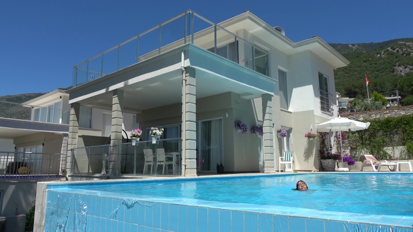 Fethiye, Turkey - 11th of June 2020: 4K Private villa and a child swimming in overflowing infinity pool
