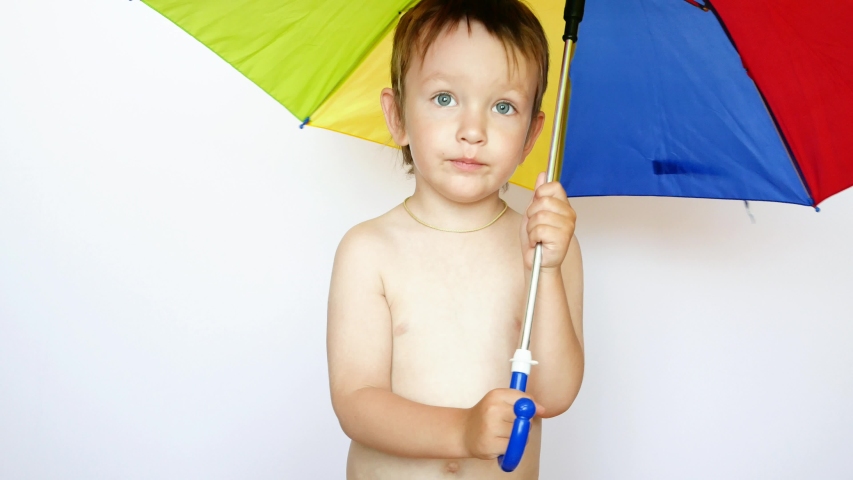 A lovely little boy stays with an umbrella against white background