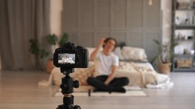 Blogging, technology and people concept - happy smiling teen blogger with camera recording video at home