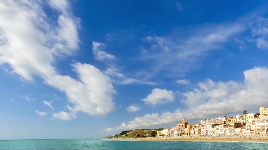 Time-lapse, moving clouds and seaside cityscape under blue sky, Barcelona, Spain