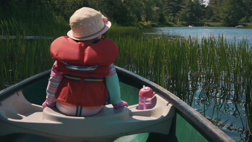 Young girl in a canoe looking at the water in slow motion.Child in a canoë enjoying nature. Family outdoor activity