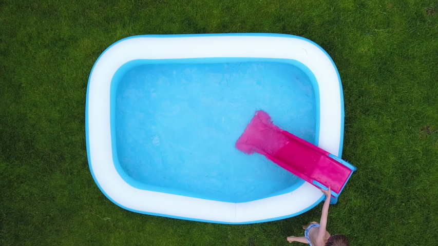 Little boy sliding and swimming in a backyard paddling pool.