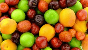 Fruit mix rotating top view background. Fresh organic macro red berry, green plum and yellow apricot fruit turning real shot 4K closeup background video  water drop.