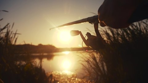 fisherman fishing fish silhouette on sunset. man lifestyle recreation with fishing rod outdoor catching fish at sunrise. hobbies fishing sport concept sunset. man relaxes with fishing rod