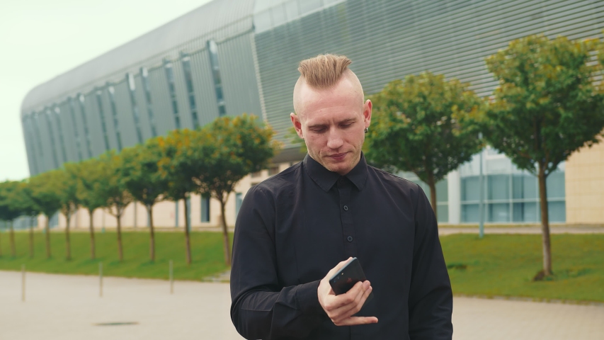 Caucasian businessman working with a mobile phone on the street In the background, two women who are also working. Remote work with a mobile phone.