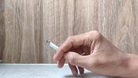 hand holding cigarette, video clip quality 4k with wooden wall background slow motion
