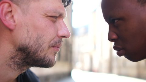 Close portrait of angry men, interracial portrait. Side view of a white man aggressively looking at a black man. Stop racism