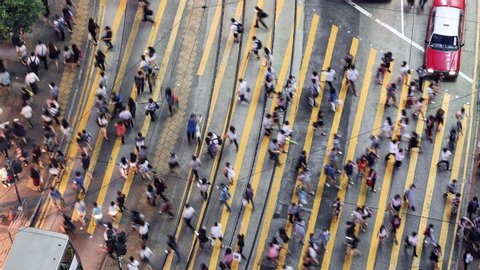 TL/ZO Asia, China, Hong Kong, 11-15-2019, Zoom Out Time lapse of people crossing the road using Pedestrian crossing in central shopping district during evening rush hour, aerial view