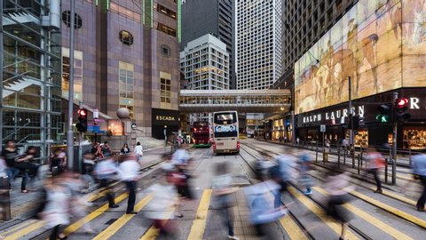 TL/ZI China, Hong Kong, 11-10-2019, Zoom In Time lapse of people crossing the road in the financial district, during evening rush hour, with traffic passing by.