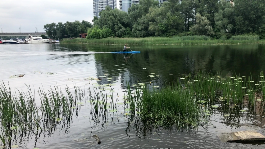 View of the Riviera Riverside, a residential complex near the bridge across the Dnieper and motor yachts on the pier. Canoe floats on the river. A man controls a kayak. Kiev, Ukraine.
