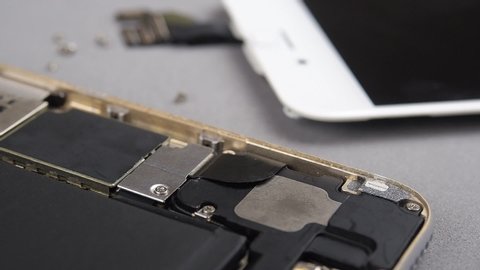 Locked down and close up of technician or engineer repairing or replace new parts of broken and damaged smartphone on desk.