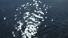 Beautiful blurry defocused dark blue sea water with sun light reflected on surface of waves. Abstract natural 4k video background.