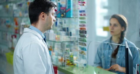 pharmacist man advises the buyer. pharmacist and a woman buyer are in a pharmacy,  a pharmacist sells her medicine. Buyer Settle Through Phone