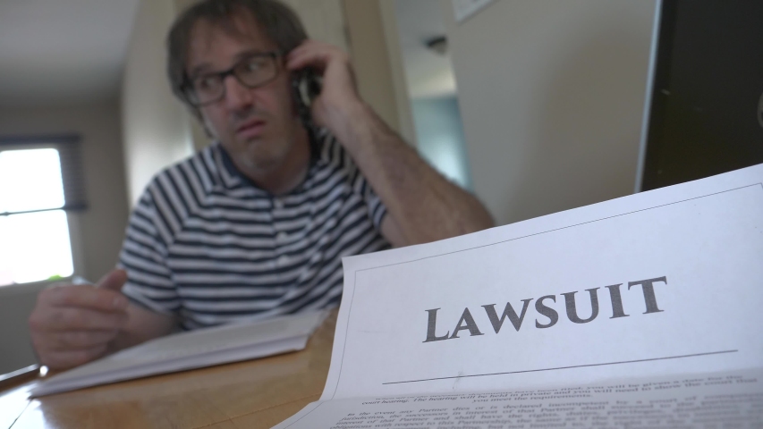 Man on the phone arguing about a lawsuit he received by mail. He is angry and anxious about the letter. Royalty-Free Stock Footage #1055067440