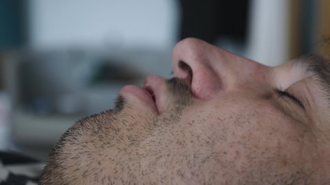 Closeup on a face of a man facing up snoring during the night in his sleep.