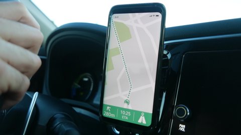 The driver of a vehicle using the GPS of his smartphone to navigate in his car. Closeup on the mobile device being used.