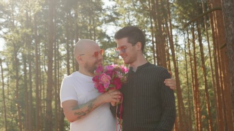 Gay wedding concept. Two men with flower bouquet and ring on finger smile and hug. Portrait of queer couple happy together. Relationship Goals. LGBTQI, Pride Event, LGBT Pride Month