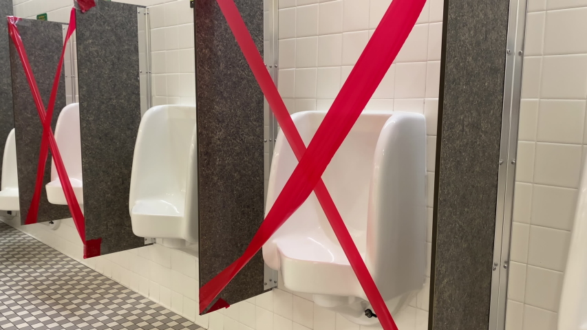A man walks up to a urinal in a men