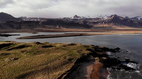Aerial Drone view of Iconic Budir beach near Budir Black Church in West Iceland in dramatic weather with snowy mountains and stormy clouds in the background