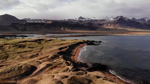 Aerial Drone view of Iconic Budir beach near Budir Black Church in West Iceland in dramatic weather with snowy mountains and stormy clouds in the background
