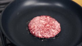 Raw beef cutlet frying on hot pan in close up.Natural minced ground meat cooking in home kitchen for dinner meal.Footage of fresh patty preparation for traditional American pork burger dish