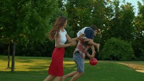 Positive family running in green field. Happy children and parents playing with ball in meadow. Smiling father carrying son on shoulders. Cheerful mother and daughter trying to get ball during game