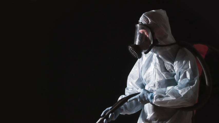 Caution Disinfection is in Progress. A man in a protective suit, glasses and a respirator sprays a disinfectant. At the same time, he makes gestures symbolizing the ban on presence Royalty-Free Stock Footage #1055076077