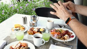Man with Mobile Phone in Hands Arranges Beautiful Dishes, Drinks and Food to Take Photos and Make a Video with Breakfast in Hotel. Blogger Making Videos for His Followers on Social Networks